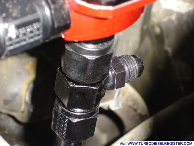 fitting on return side of regulator used to tie injector return into